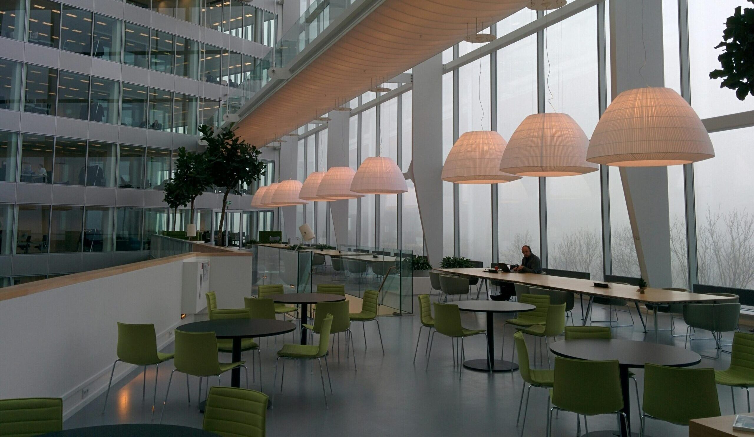 Contemporary office interior with large windows and stylish furniture, featuring a foggy exterior view.